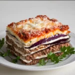 A traditional Greek moussaka with layers of golden-baked eggplant, spiced meat sauce, and creamy béchamel, served in a casserole dish