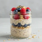 A jar of creamy overnight oats topped with fresh berries, nuts, and a drizzle of honey, perfect for a healthy breakfast